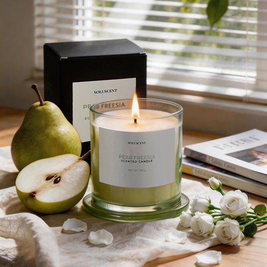 Soluscent Pear Freesia soy candle lit beside its box with fresh pear and white flowers