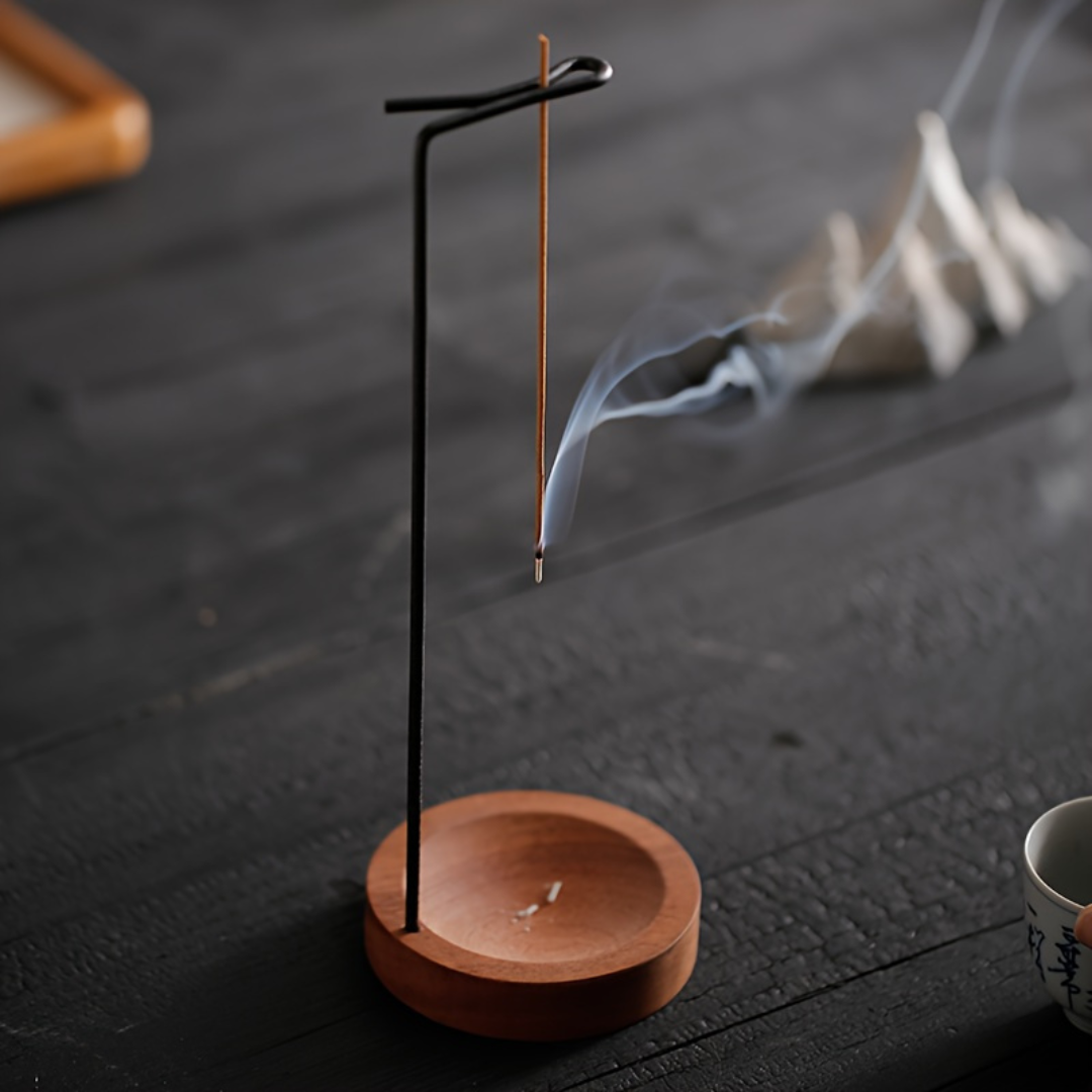 Incense stick on a wooden stand with smoke on a dark surface