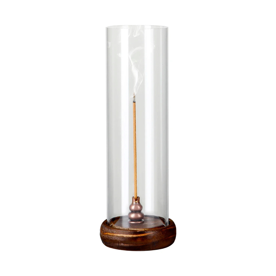 Incense stick in a glass cylinder with wooden base on a white background