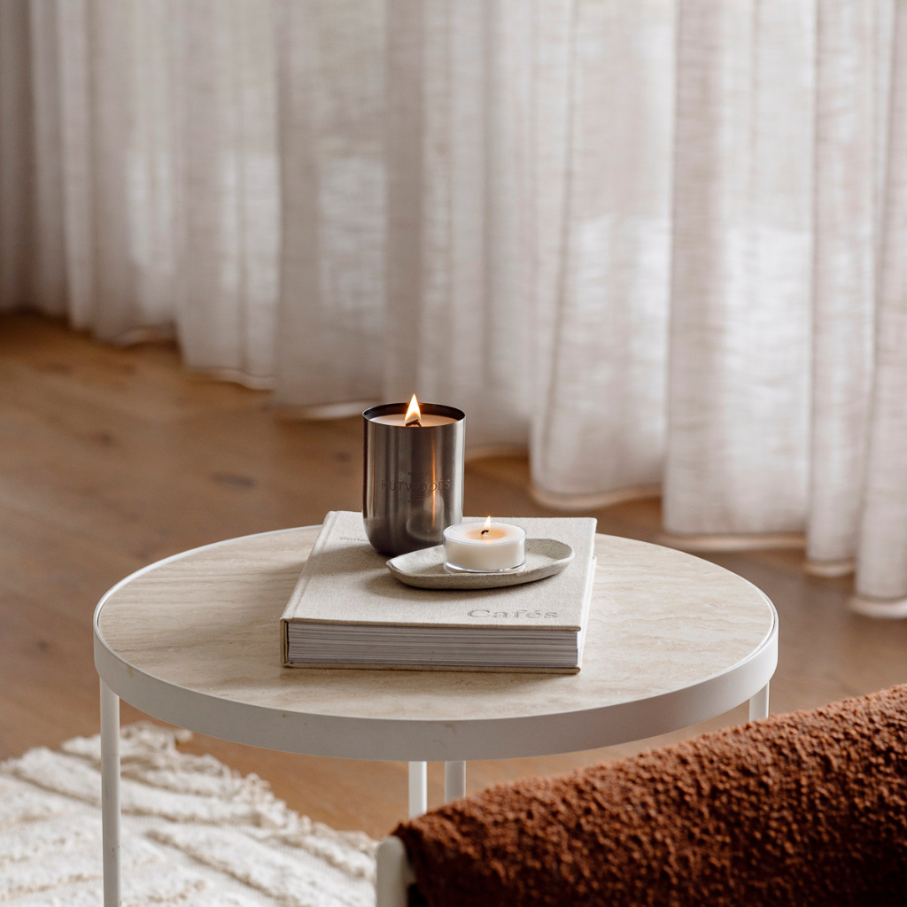 Hutwoods candle burning on a coffee table in a warm neutral living room