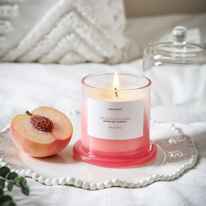 Soluscent Peach Oolong candle burning beside fresh peach