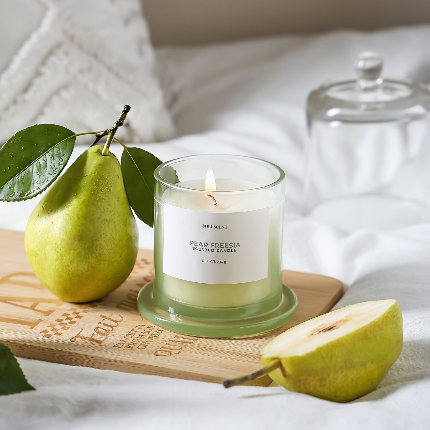 Soluscent Pear Freesia candle burning beside fresh pear