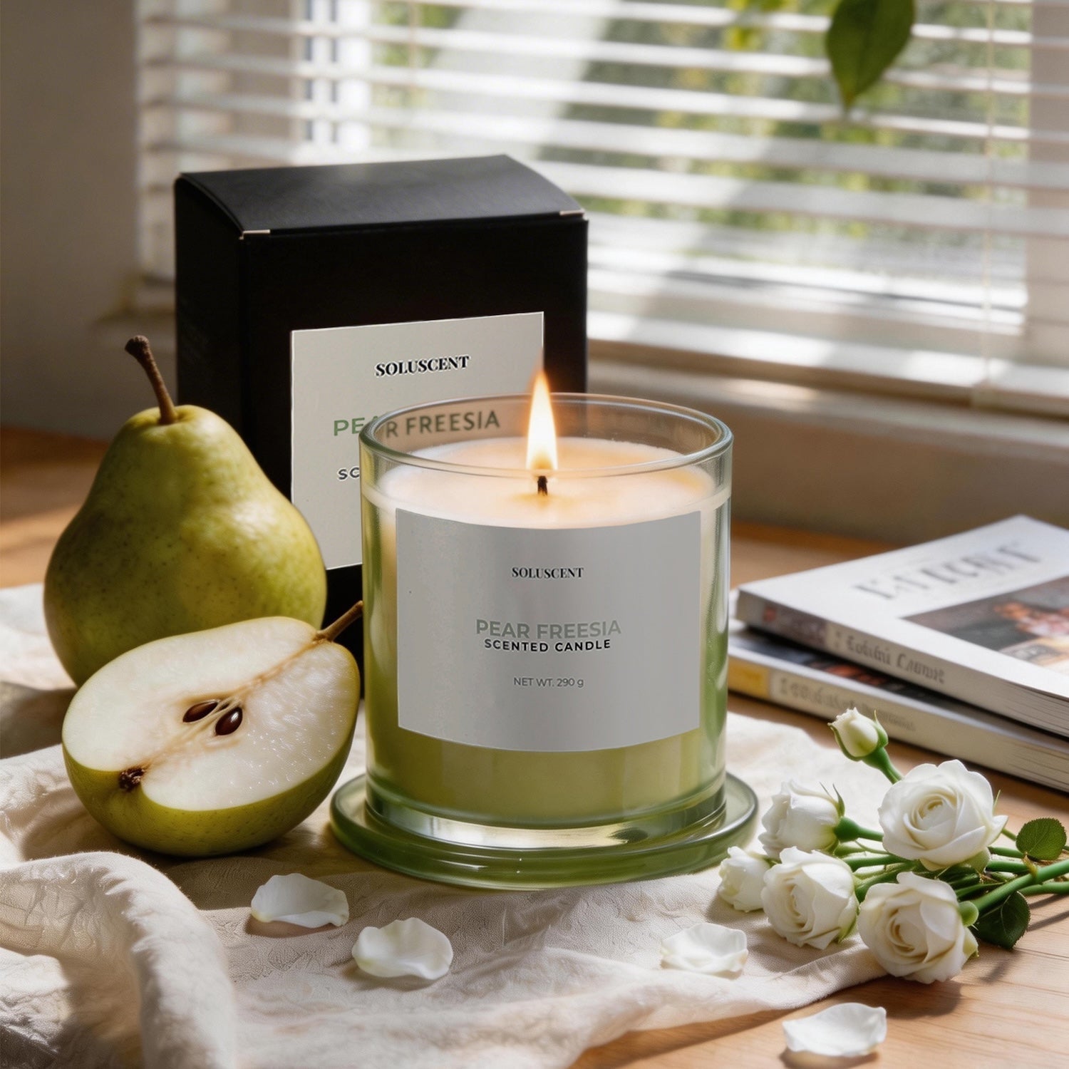 Soluscent Pear Freesia soy candle lit beside its box with fresh pear and white flowers