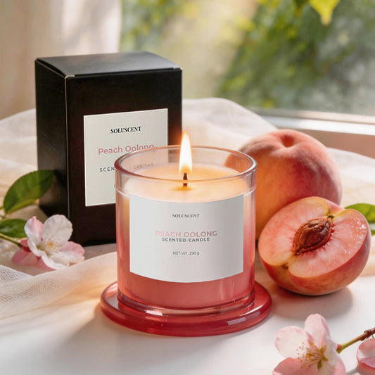 Soluscent Peach Oolong soy candle lit beside its box with fresh peach