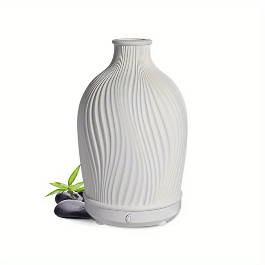 White textured diffuser on a white background with a small plant and stones.
