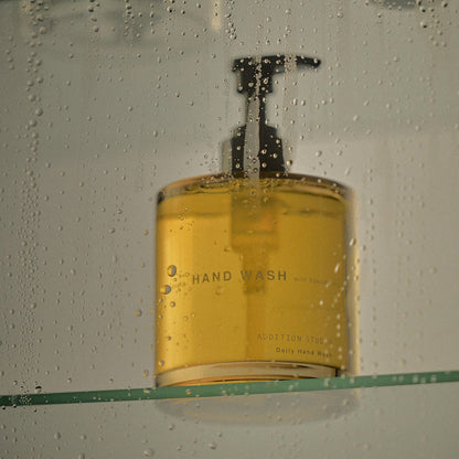 Addition Studio Hand Wash 390mL amber pump on glass shelf with water droplets