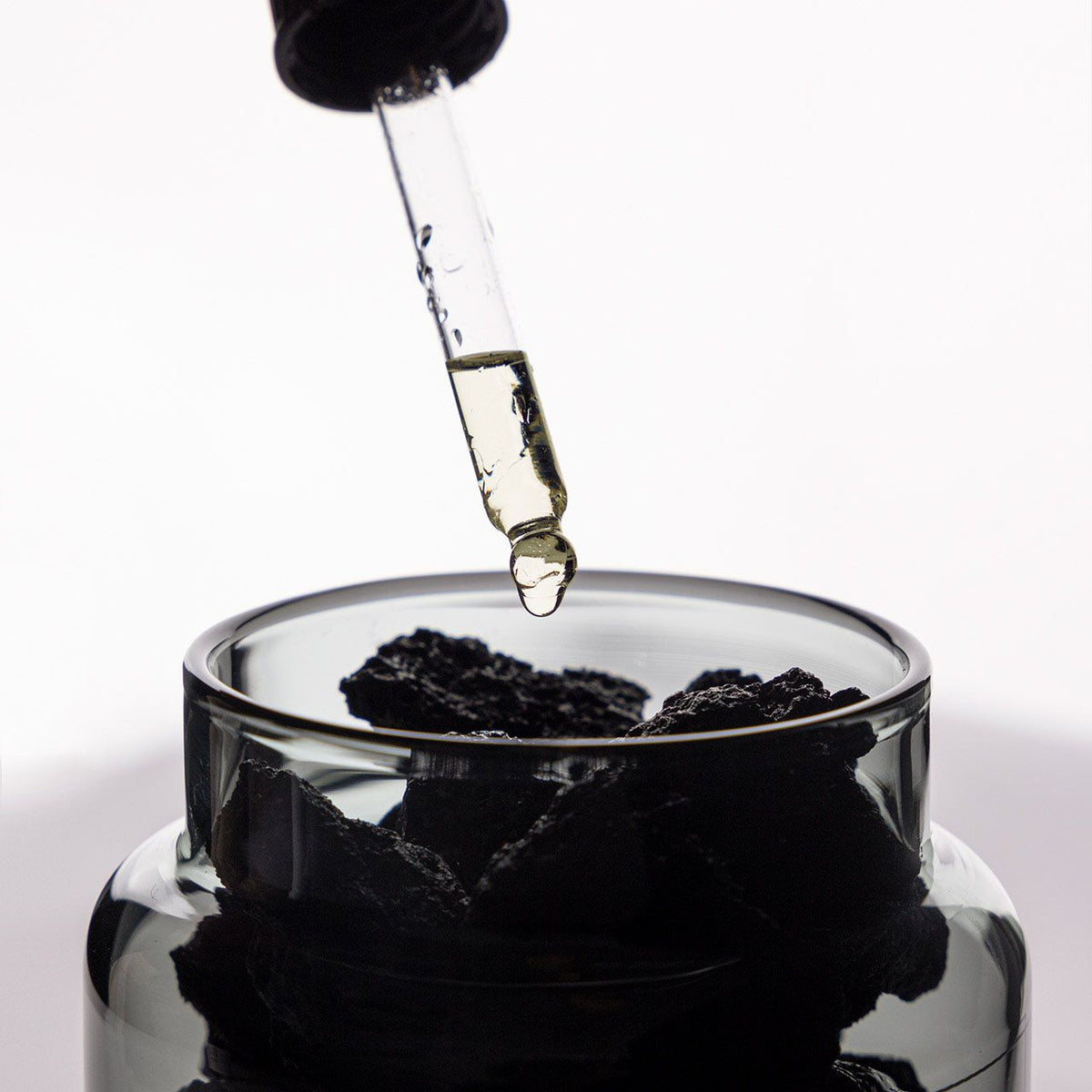 Studio Milligram volcanic rock Study of Trees top-up fragrance oil being applied to dark scoria