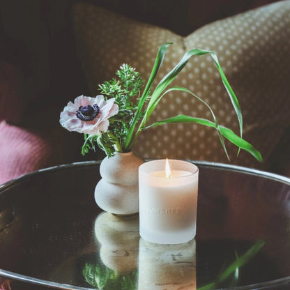 Cowshed Indulge Candle styled with flowers
